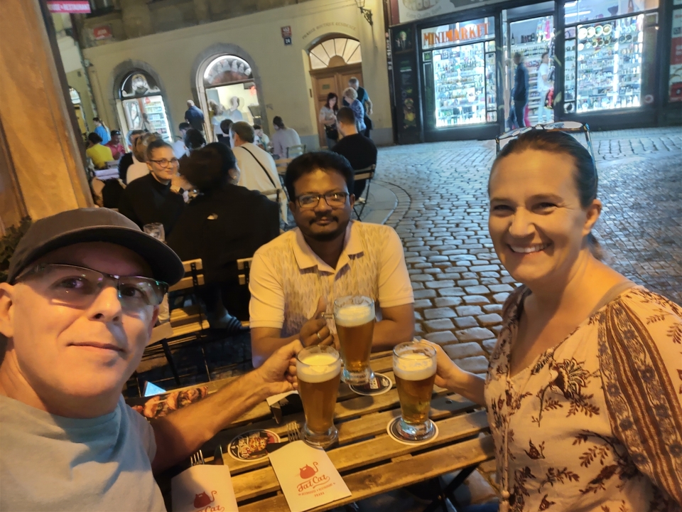 Groupe de personnes savourant des bières dans un café en plein air la nuit.