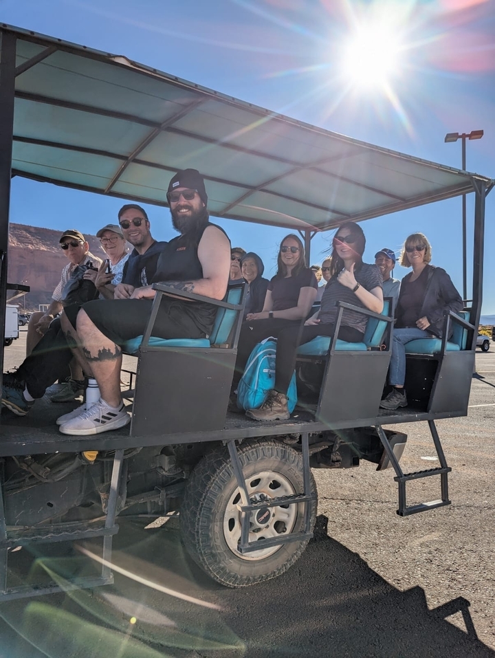 Un groupe de personnes dans un véhicule ouvert lors d'une excursion avec un paysage rocheux en arrière-plan.