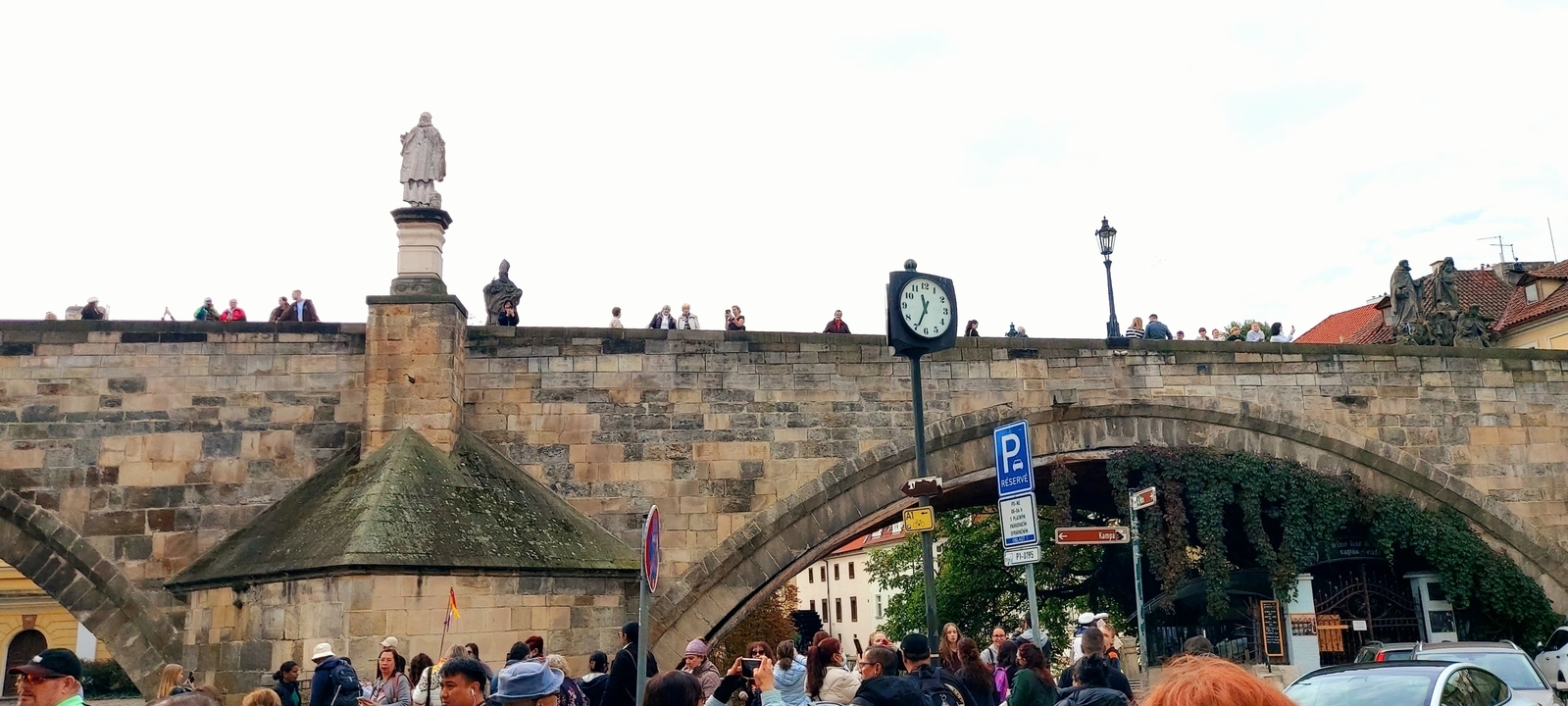 Zone piétonne bondée près d'un pont historique.