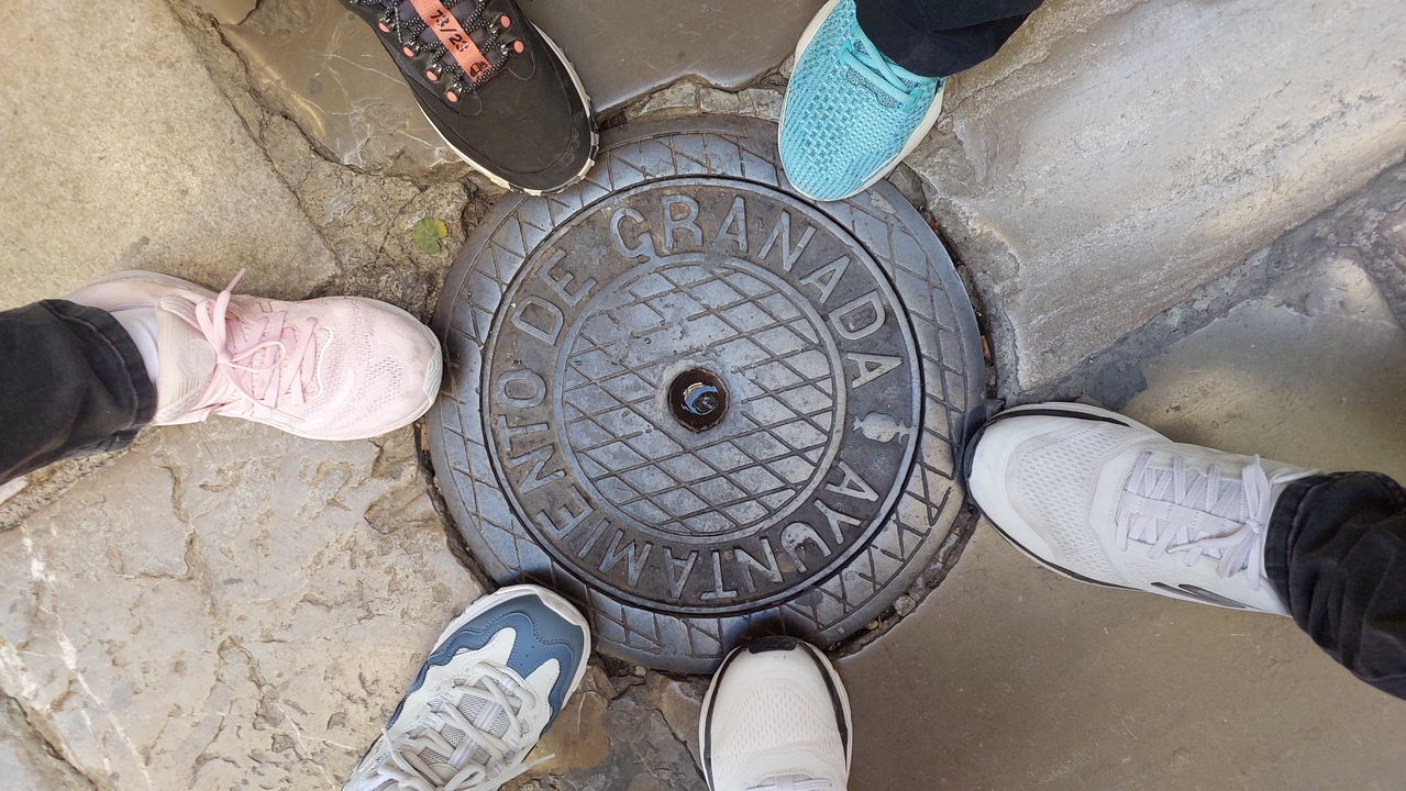 Gros plan d'une plaque d'égout avec des chaussures autour.