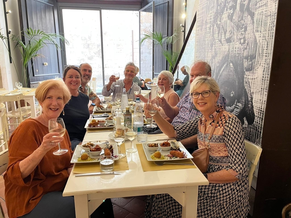 Groupe de personnes à une table de restaurant trinquant avec des verres de vin.