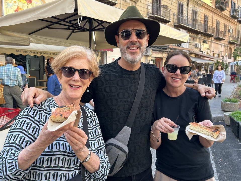 Trois personnes savourant de la nourriture de rue dans un marché.
