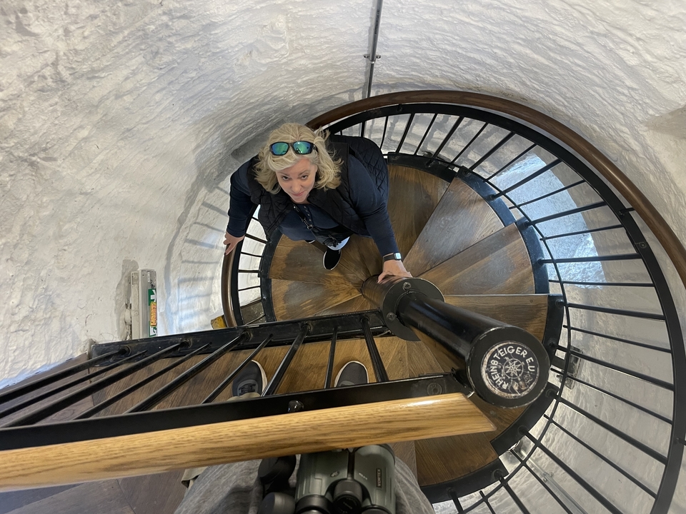 Femme gravissant un escalier en colimaçon à l'intérieur d'une tour.