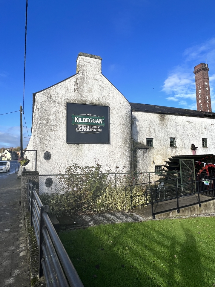 Panneau de l'Expérience de la Distillerie Kilbeggan sur un bâtiment en pierre blanche.