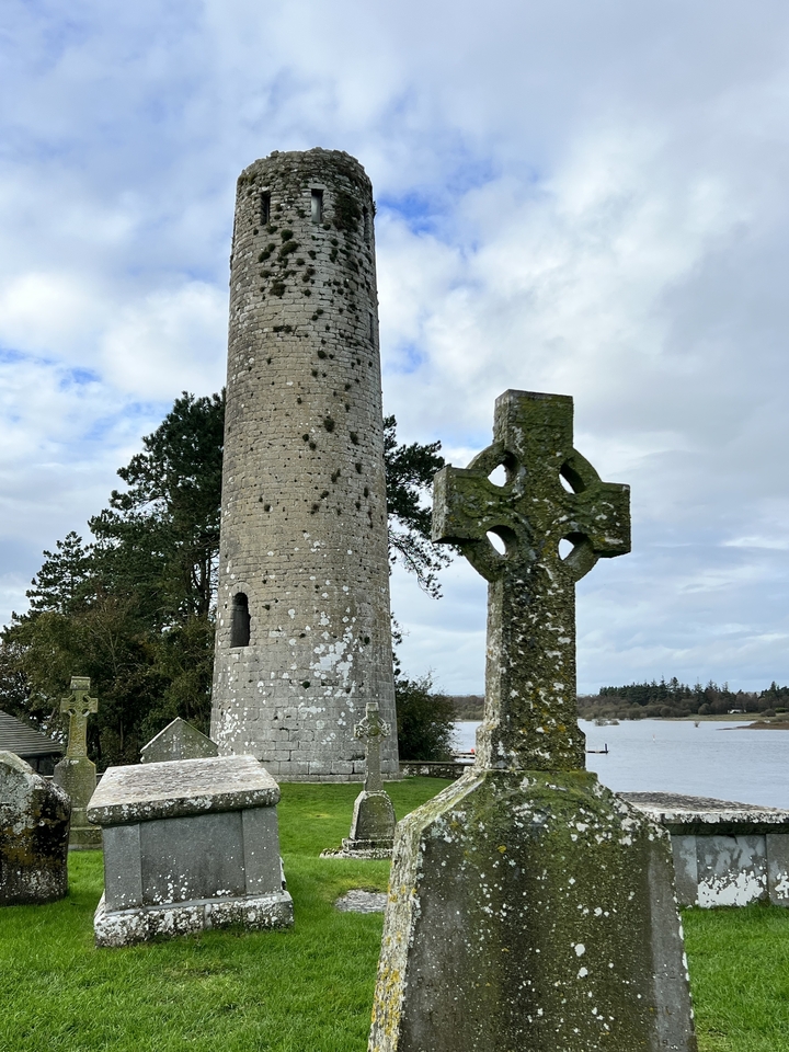 Tour ronde et croix celtique dans un cimetière.