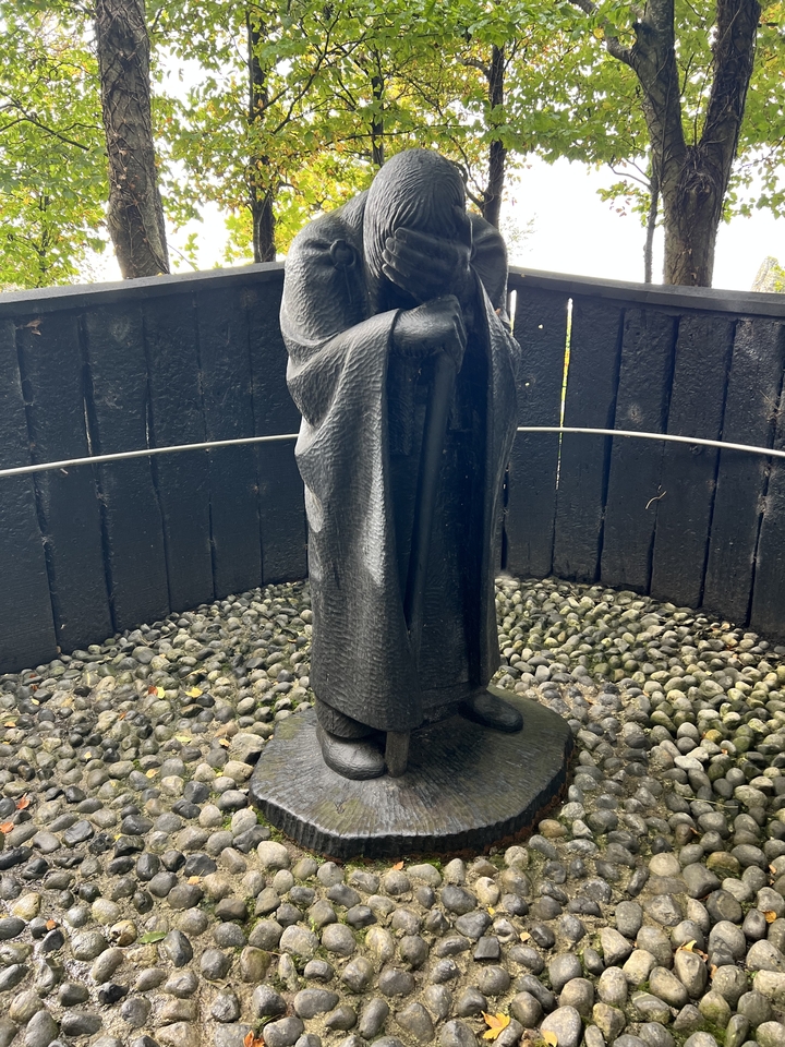 Une statue noire entourée de galets et d'une clôture en bois.