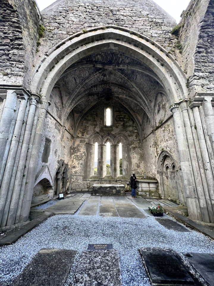 Une personne debout dans une grande ruine de pierre avec des arches.