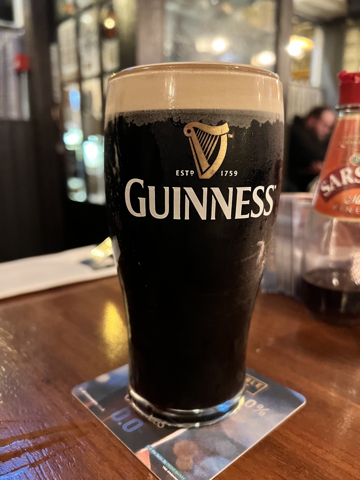 Une pinte de bière Guinness sur une table en bois.