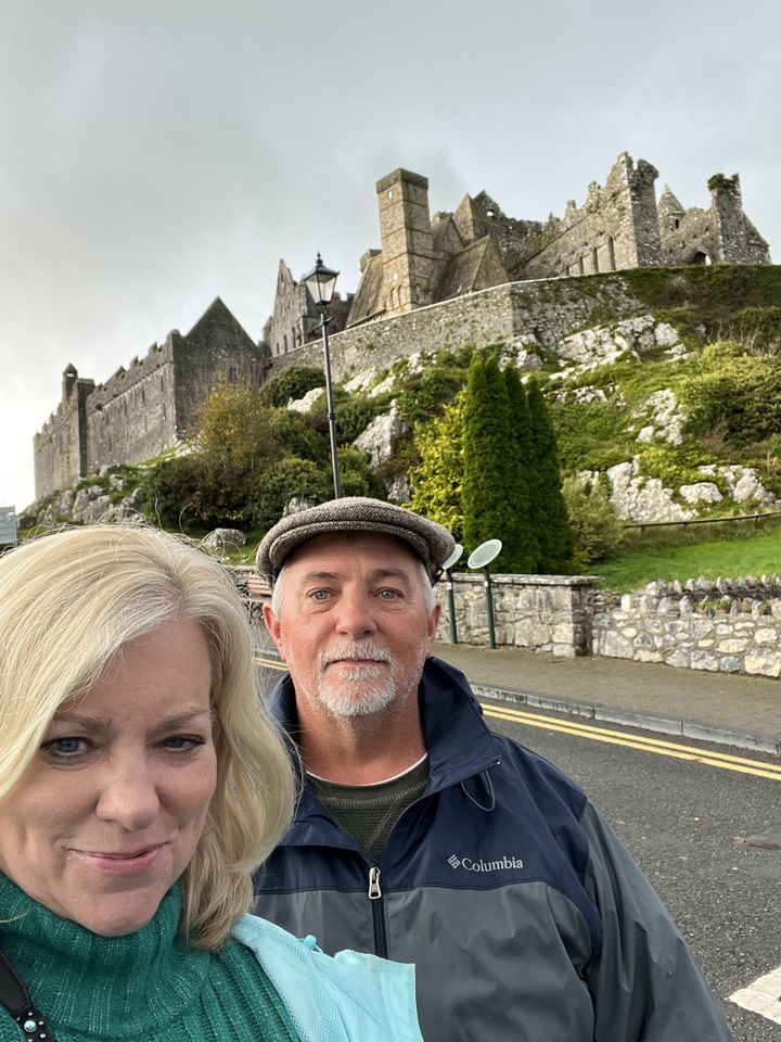 Un couple posant devant des ruines sur une colline.