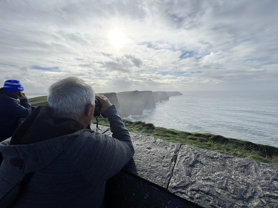 Personne observant les falaises de Moher avec des jumelles.