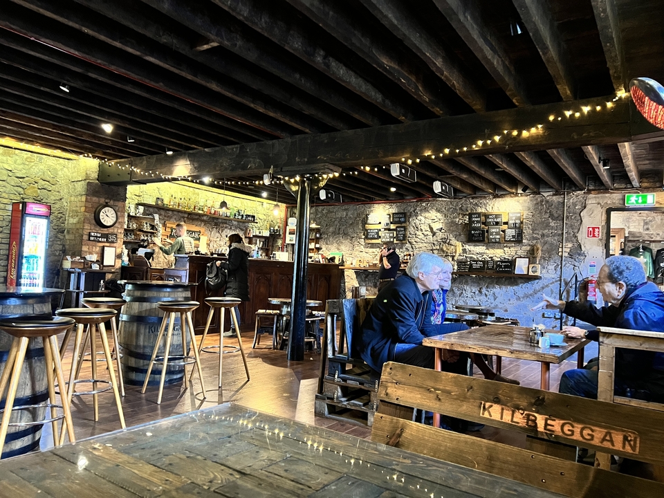 Intérieur d'une distillerie avec des personnes assises aux tables et un espace bar.