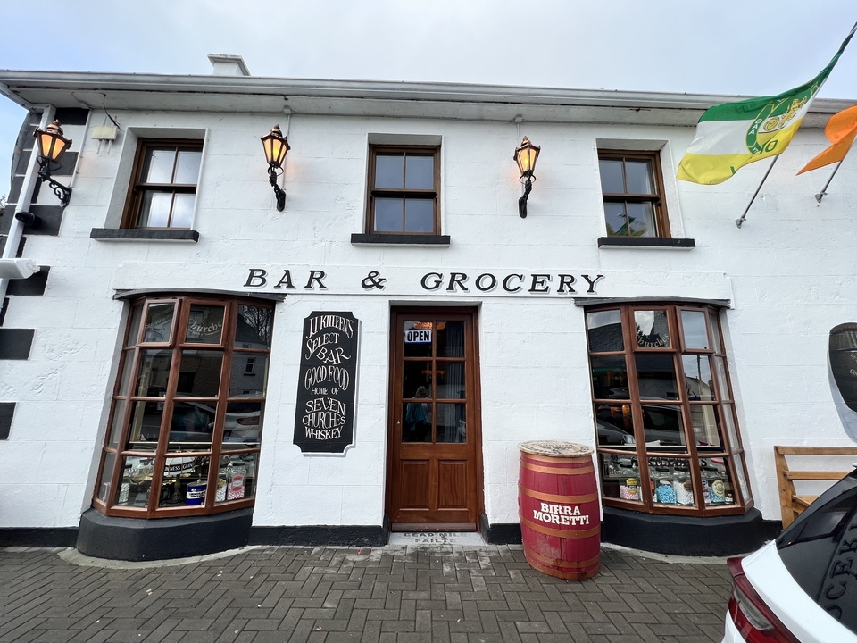 Pub irlandais traditionnel avec une enseigne d'épicerie.