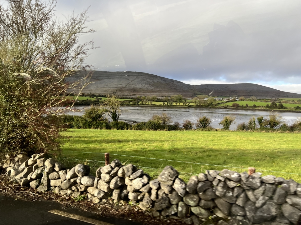 Un paysage pittoresque avec une clôture en pierre, des champs verts et des collines.