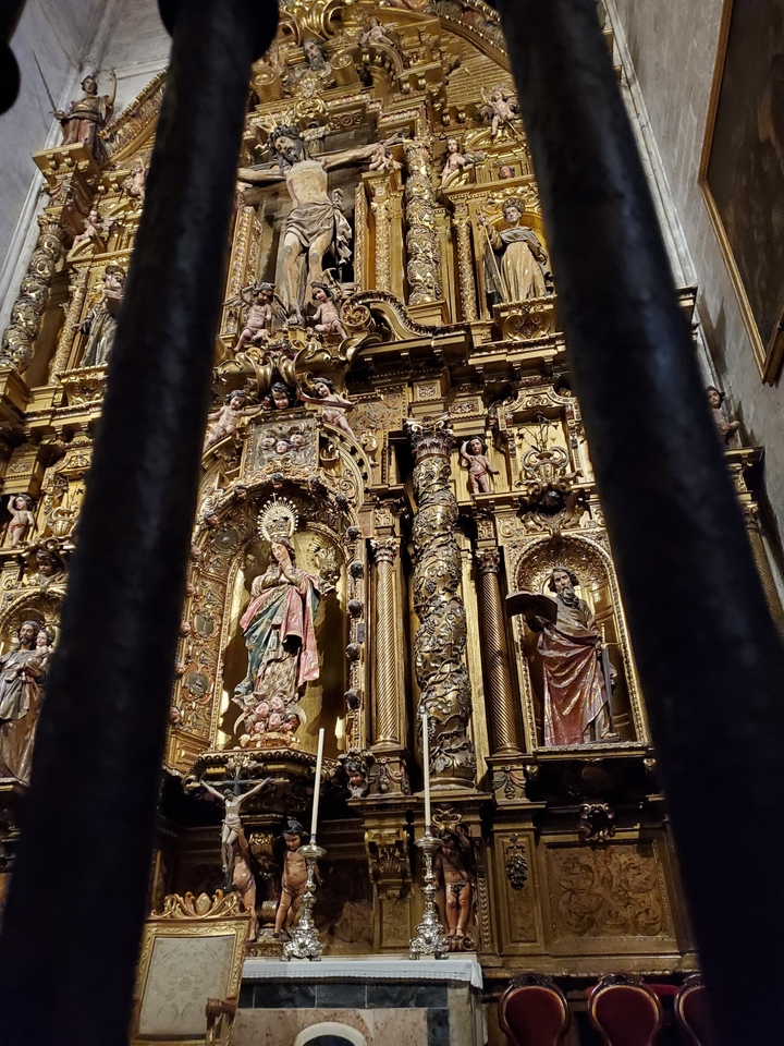 Ornate golden religious altar behind bars.