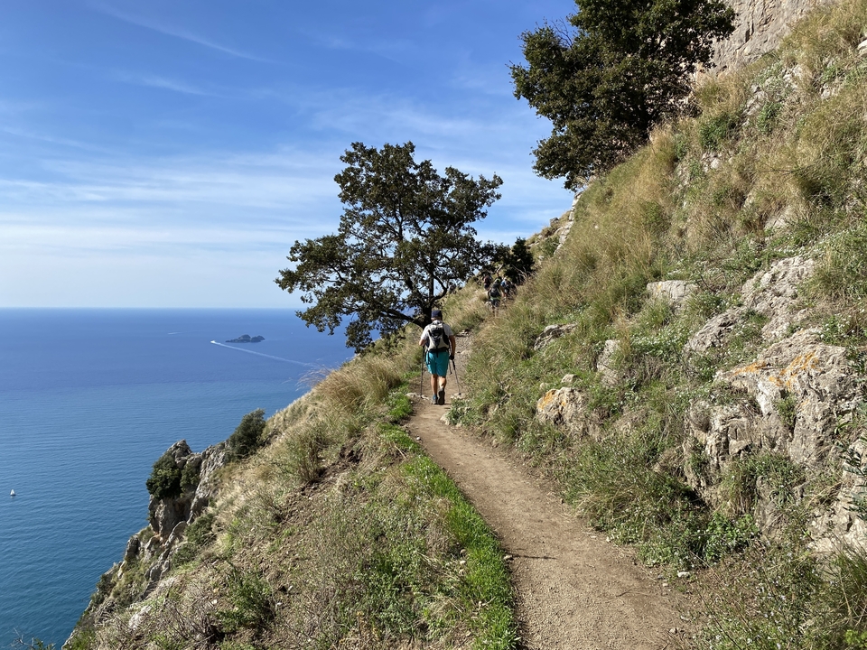 Randonneurs marchant le long d'un sentier en bord de falaise.