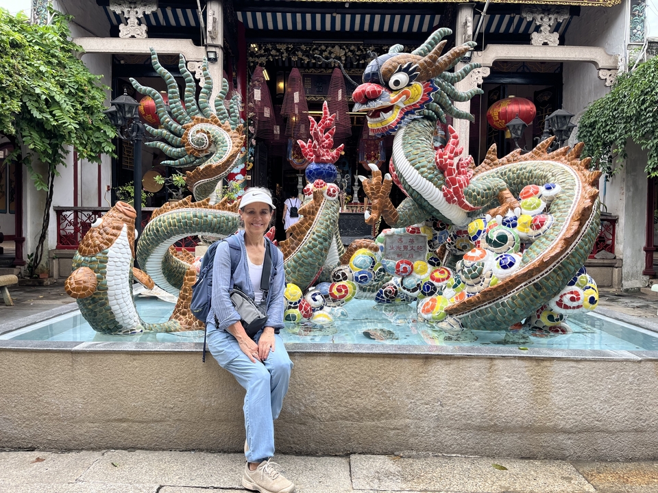 Femme posant devant une statue de dragon colorée.