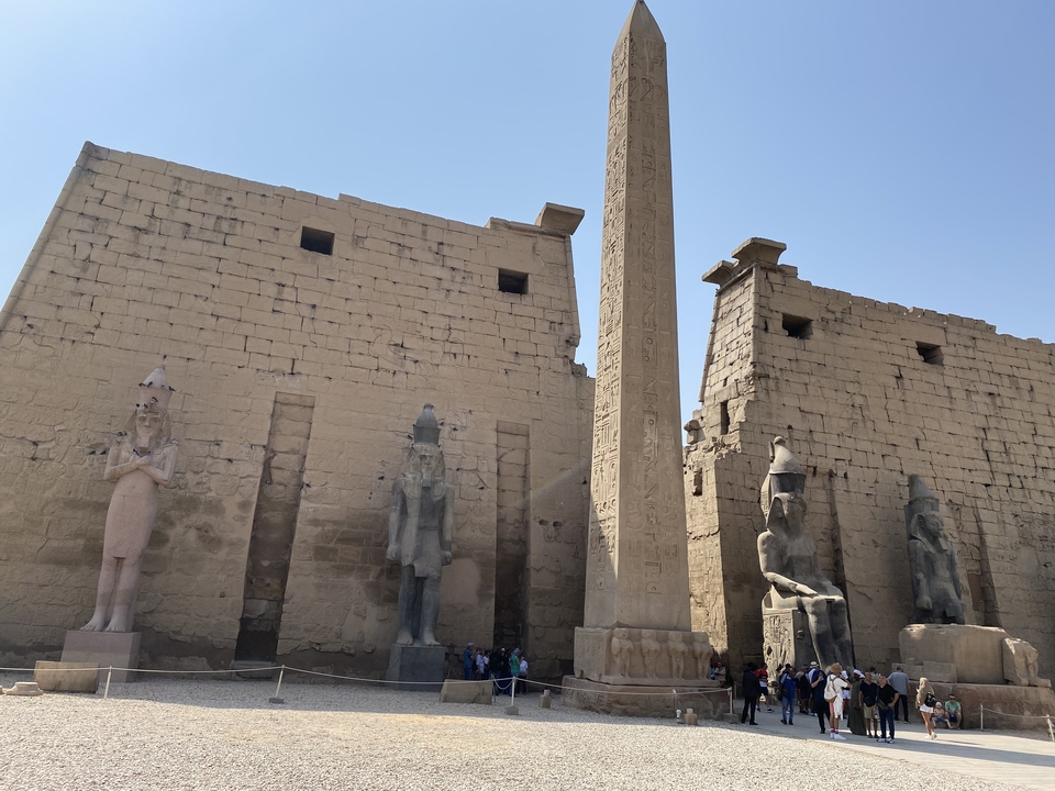 Temple égyptien antique avec statues et un obélisque.