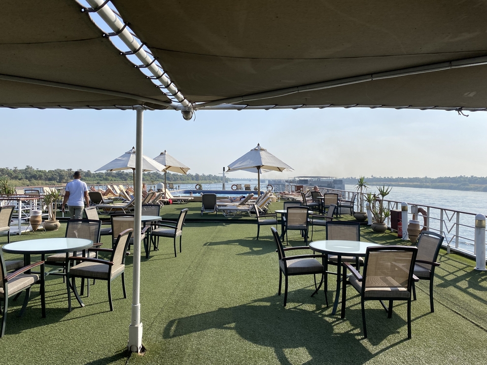 Pont d'un navire de croisière avec des chaises longues and des parasols face à la rivière.