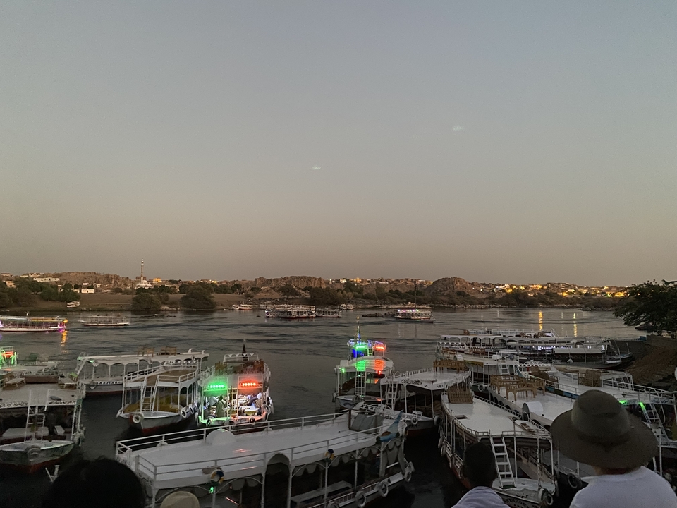 Des bateaux sur une rivière au crépuscule avec les lumières de la ville en arrière-plan.