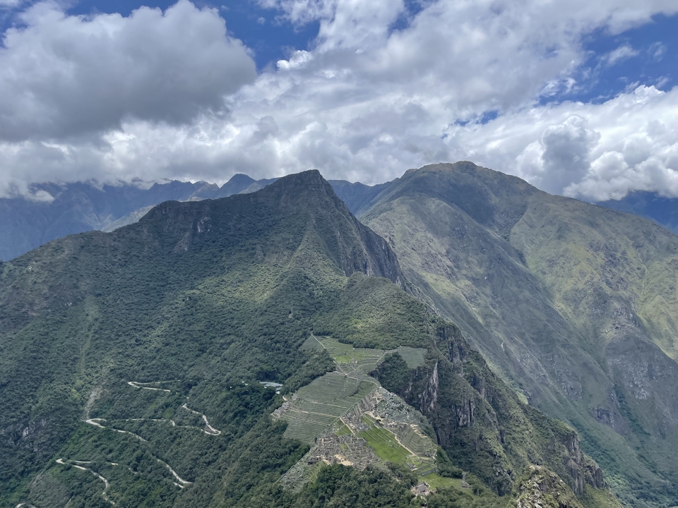 Chaîne de montagnes verdoyante sous un ciel nuageux.