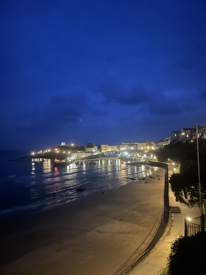Ville côtière illuminée la nuit avec des reflets dans l'eau.