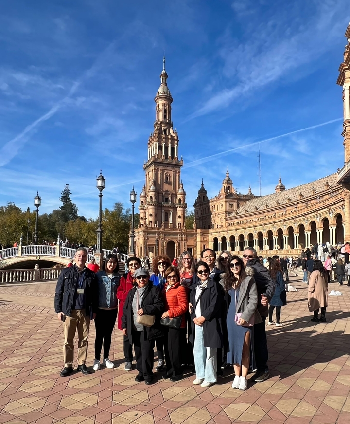 Un groupe de personnes posant devant la Plaza de España, un monument emblématique de Séville, en Espagne.