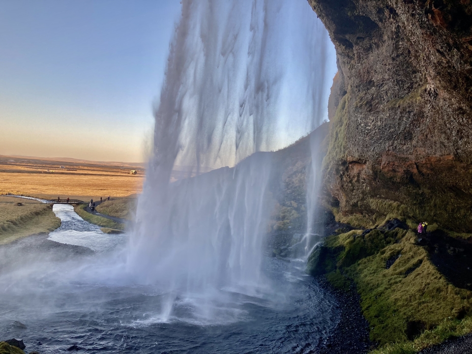 Une cascade dans un paysage pittoresque avec des champs au loin.