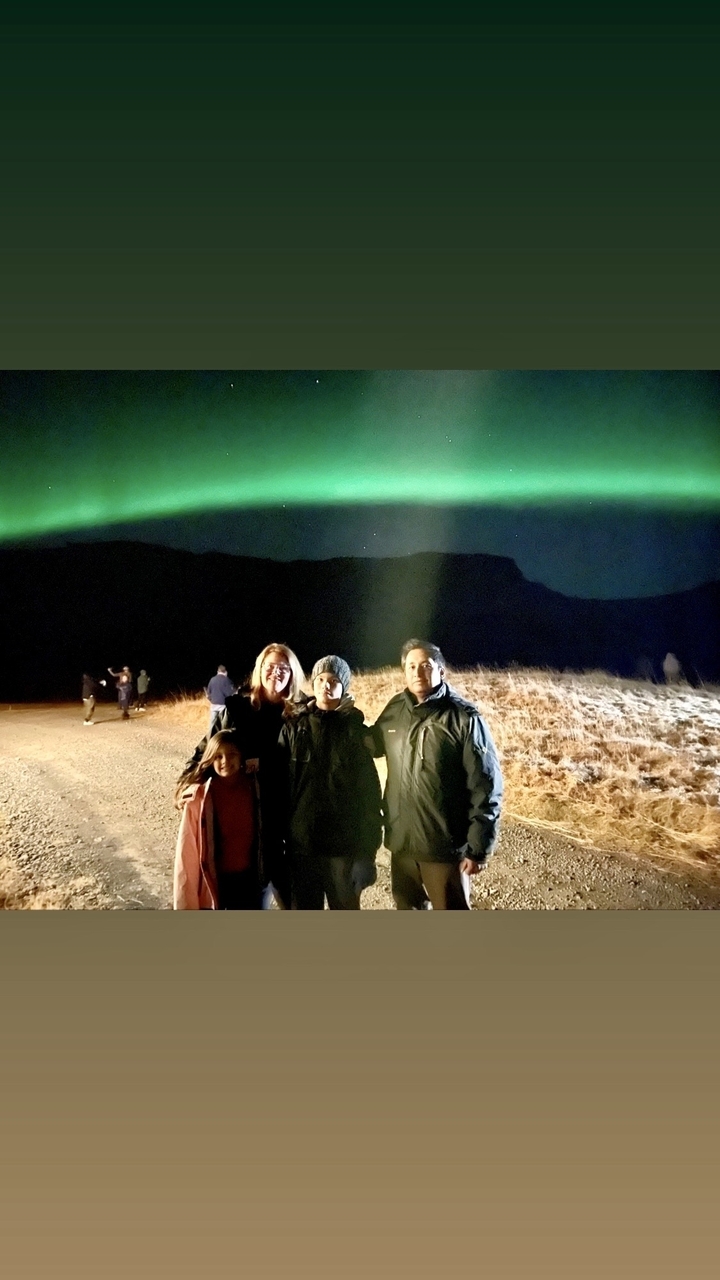 Une famille qui pose sous les aurores boréales.