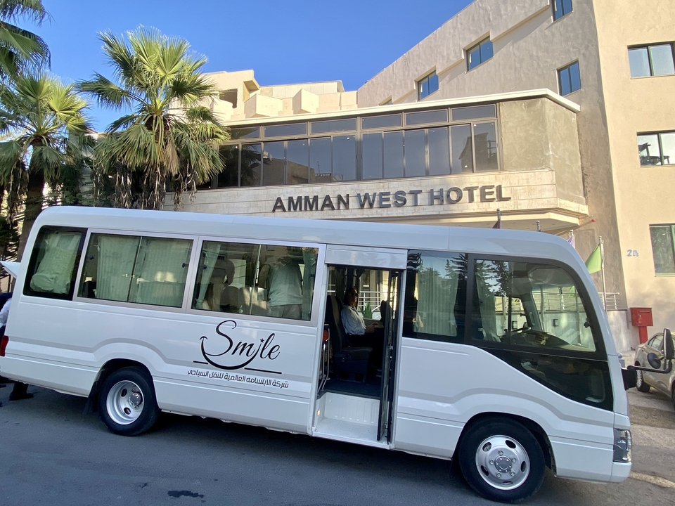 Autobus blanc garé devant un hôtel.