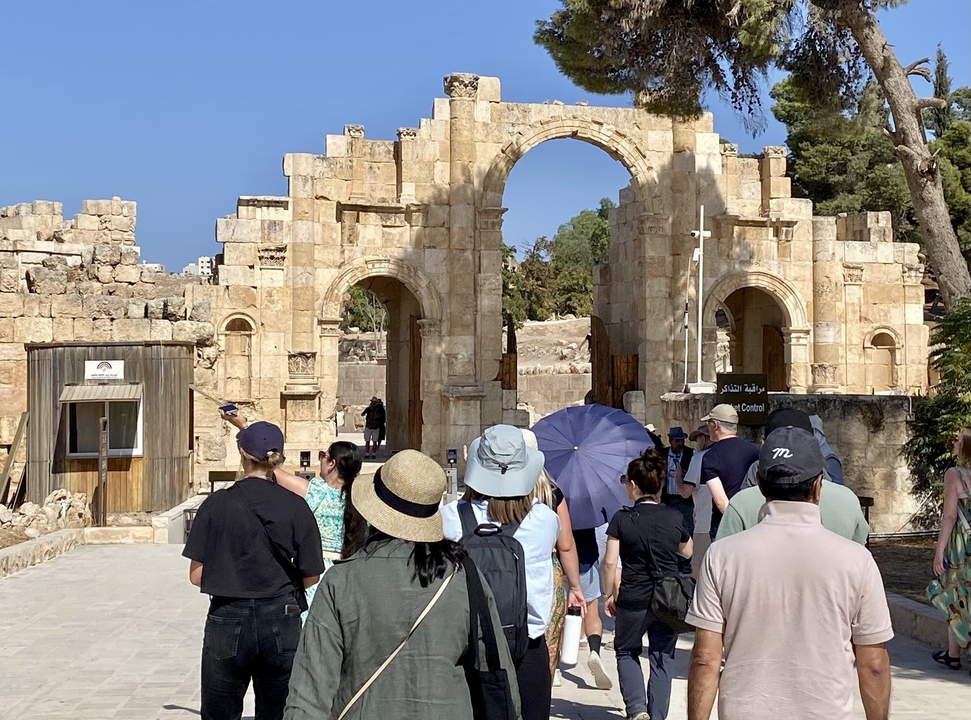 Des gens debout devant une arche de pierre ancienne.