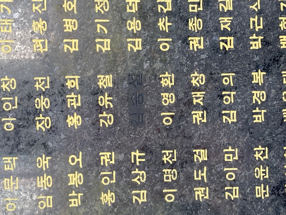 Gros plan d'un texte coréen gravé sur une pierre sombre.