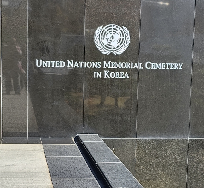 "Signalisation d'entrée du Cimetière commémoratif des Nations Unies."
Alternative translation: "Panneau d'entrée du Cimetière du mémorial des Nations Unies."