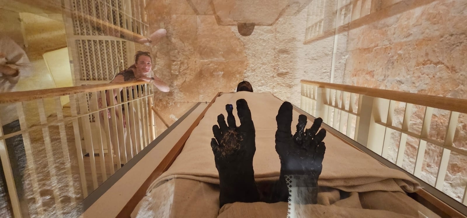 Momie conservée dans une vitrine avec une personne qui l'observe.