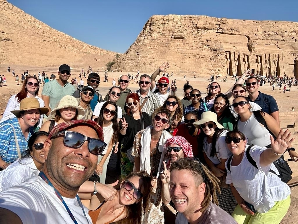 Groupe de personnes posant devant un monument antique.