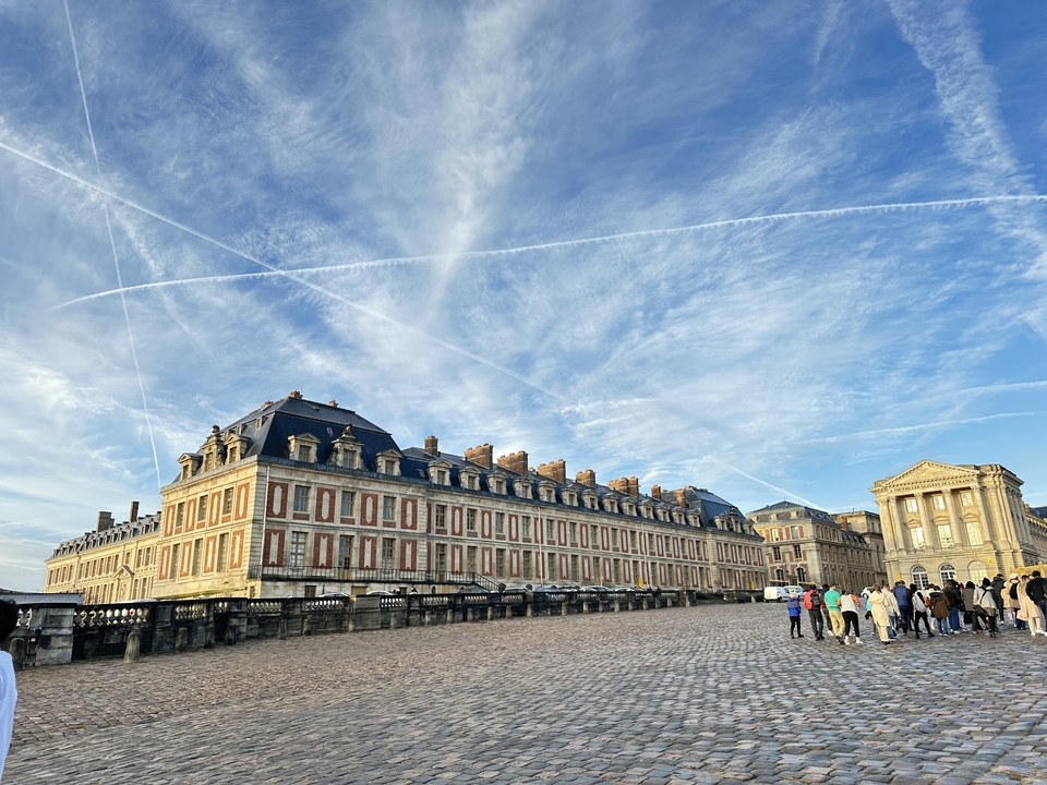 Palais avec une grande foule à l'extérieur sous un ciel clair.
