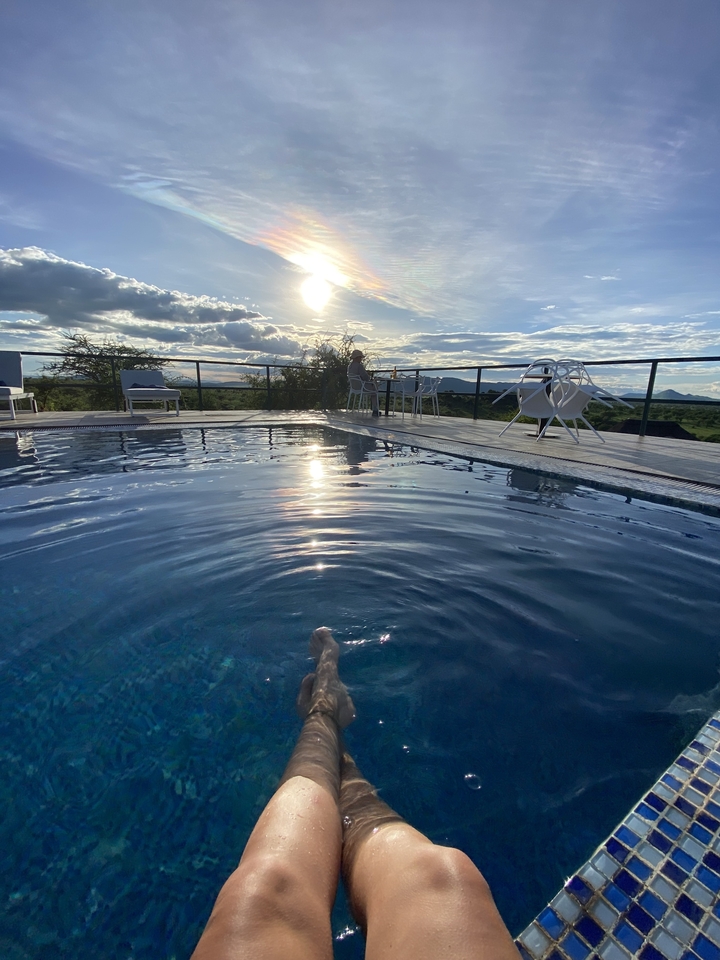 Une piscine avec une personne assise et le soleil qui se couche en arrière-plan.