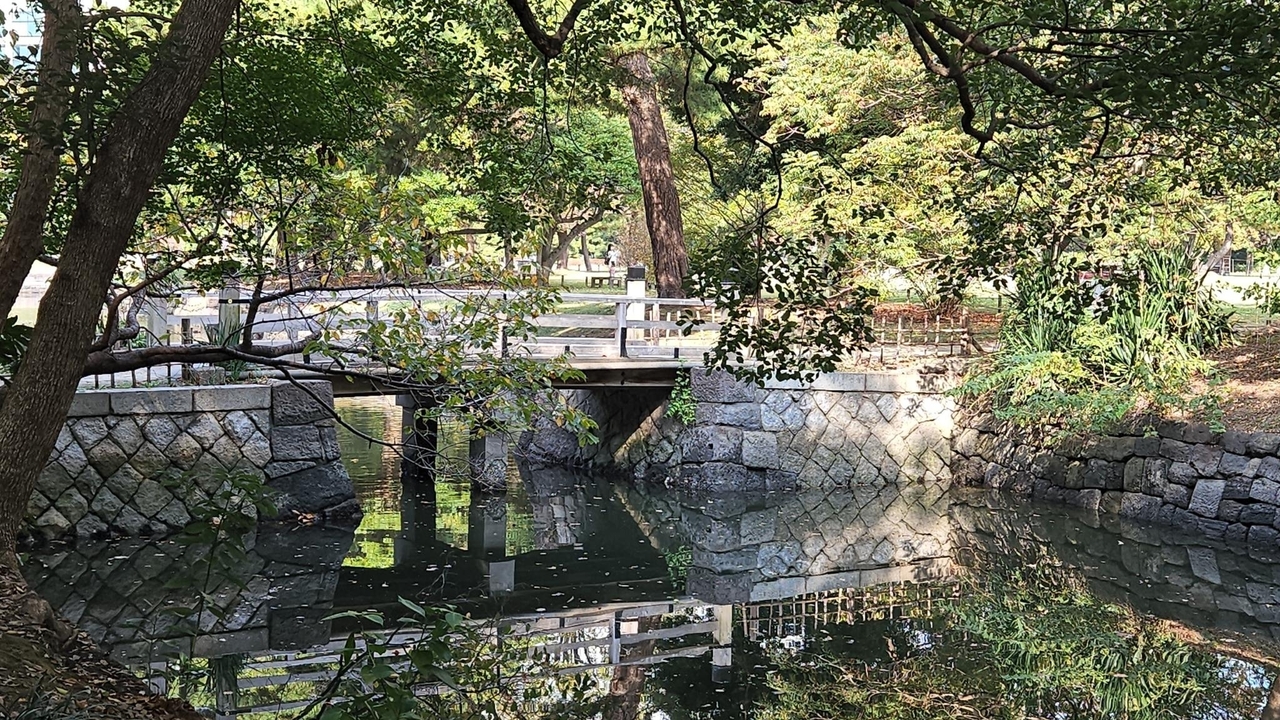 Un pont de pierre au-dessus d'une étendue d'eau calme entourée d'arbres.
