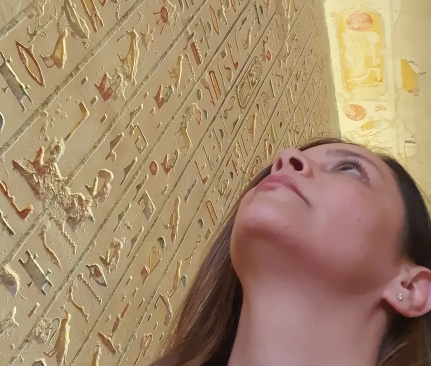 Personne regardant des hiéroglyphes égyptiens antiques gravés dans un mur.