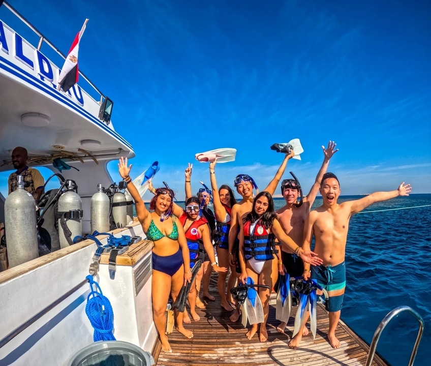 Groupe de personnes en équipement de plongée sur un bateau se préparant à plonger.