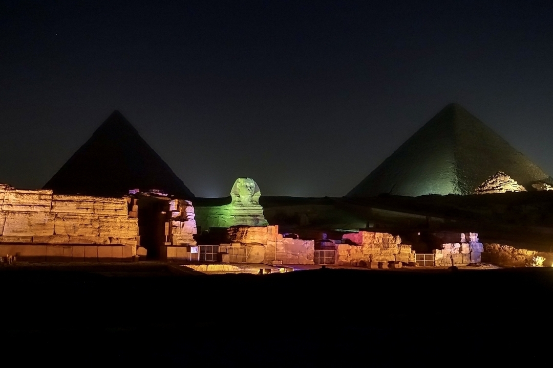 Pyramides de Gizeh et Sphinx illuminés la nuit.