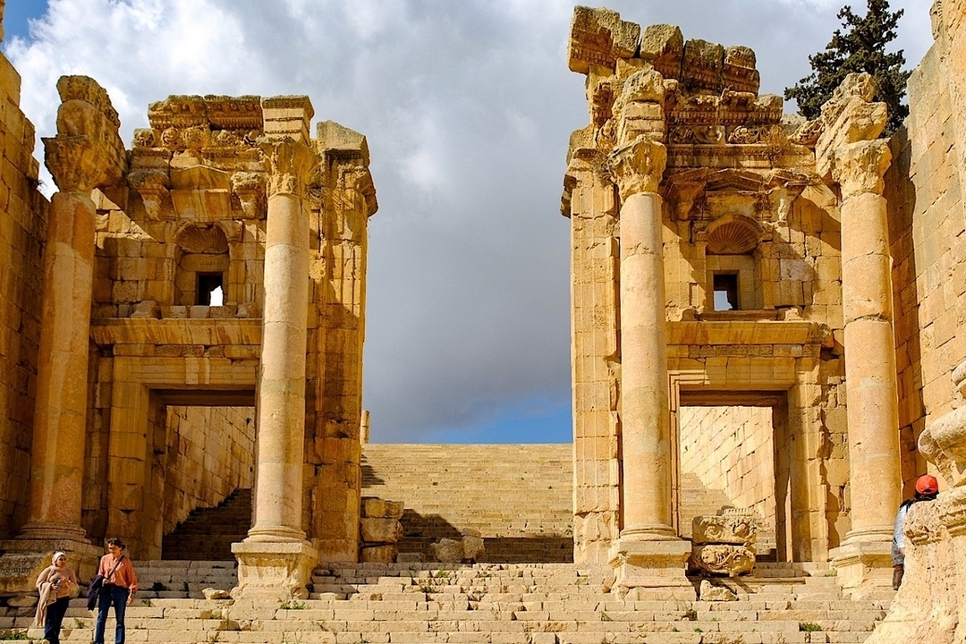 Ruines romaines antiques à Jerash sous un ciel partiellement nuageux.