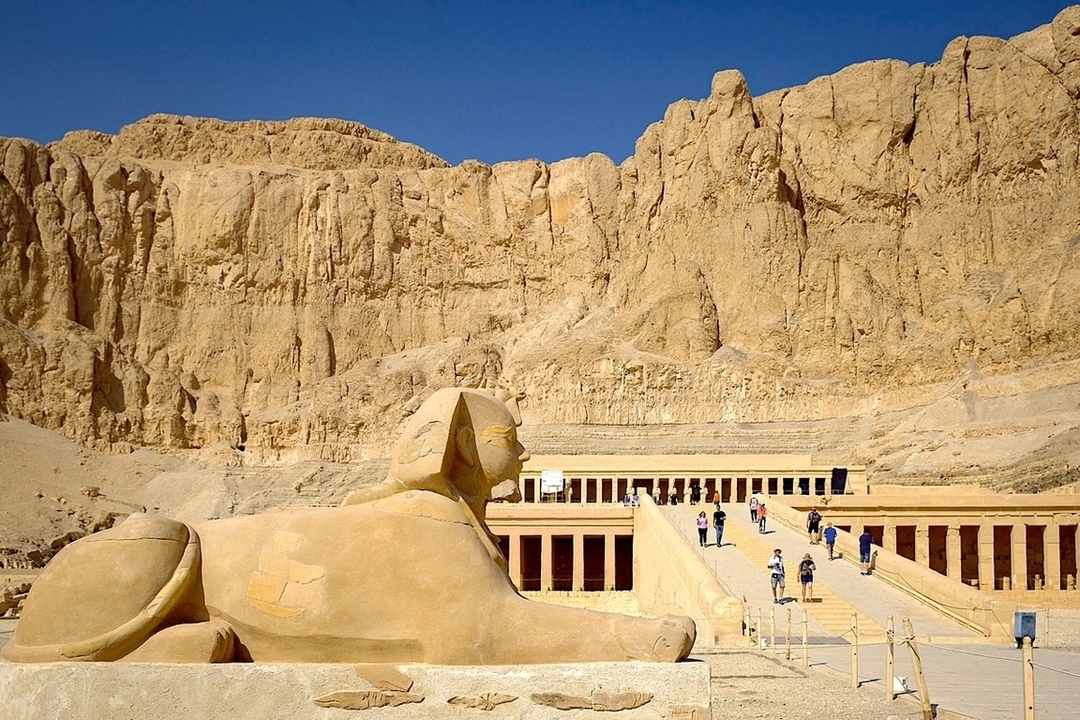 Temple d'Hatchepsout avec une sculpture de sphinx et des touristes.