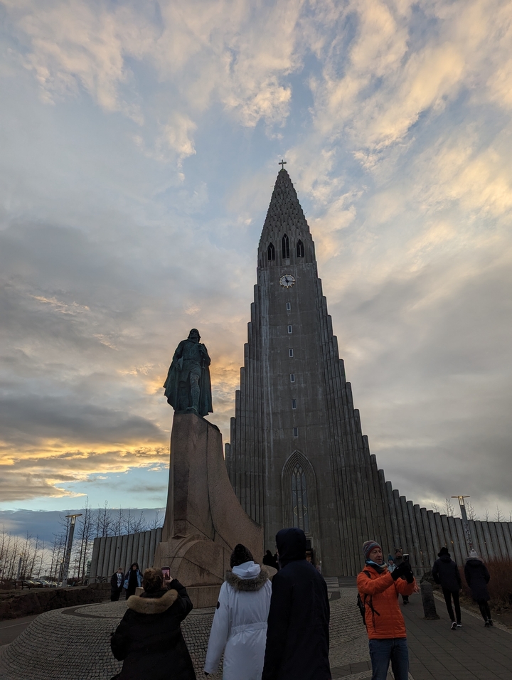 Silhouette d'une statue devant Hallgrimskirkja au coucher du soleil.