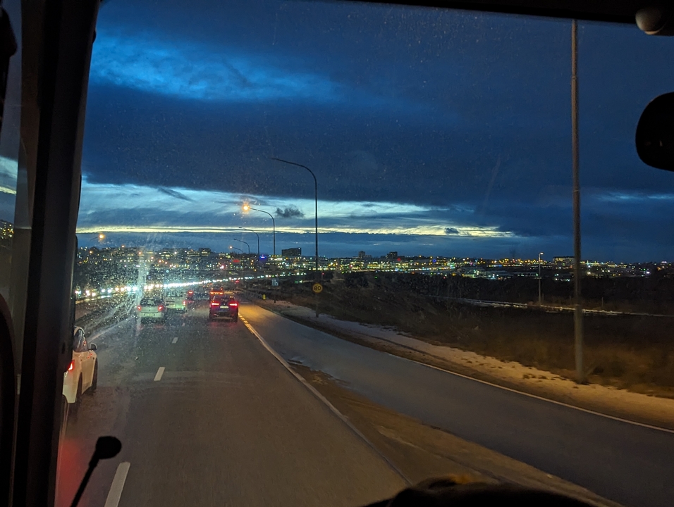 Vue nocturne depuis la fenêtre d'une voiture avec les lumières de la ville au loin.