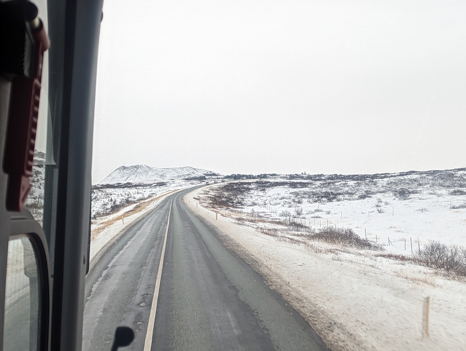 Route enneigée avec paysage montagneux au loin.