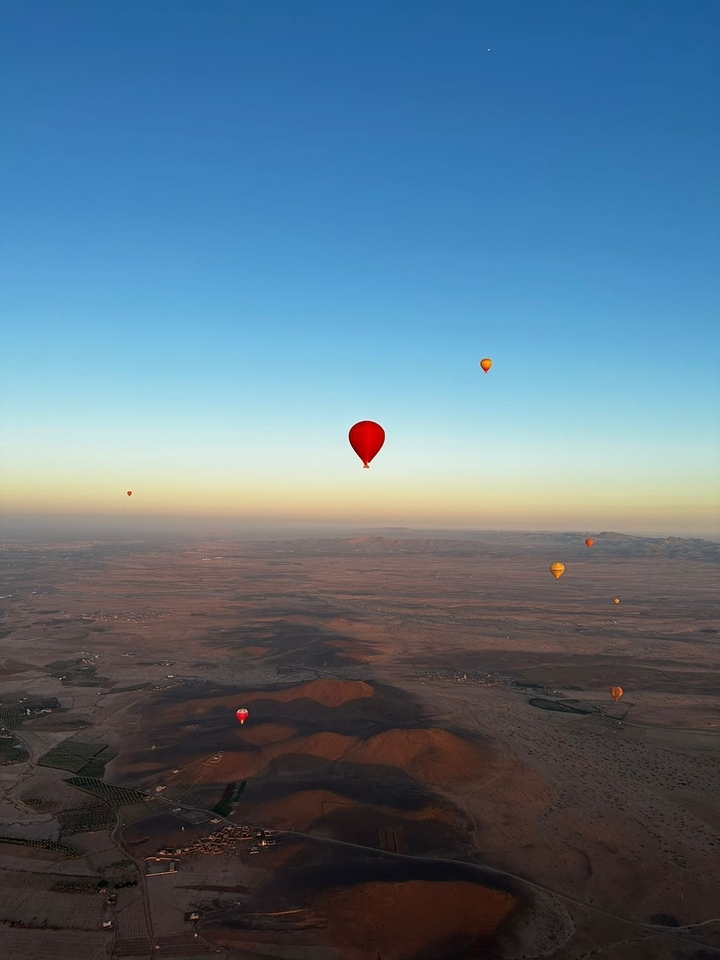 Montgolfières au-dessus d'un vaste paysage au lever du soleil.