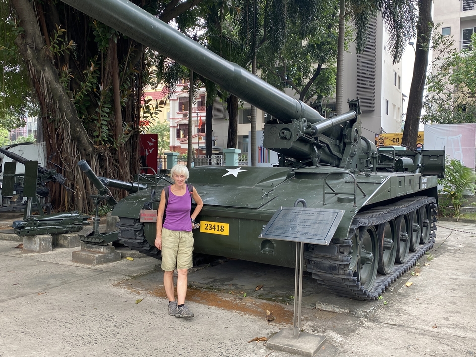 Femme debout à côté d'un char militaire à l'extérieur.