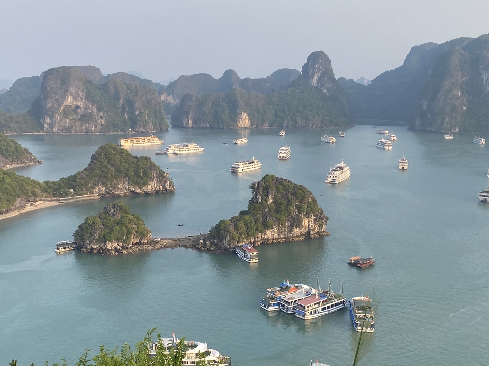 Vue aérienne de bateaux sur une eau turquoise entre des collines calcaires.