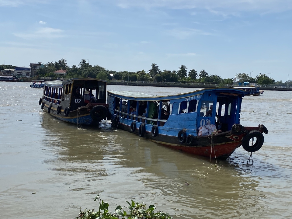 Deux bateaux reliés sur une rivière avec des gens.