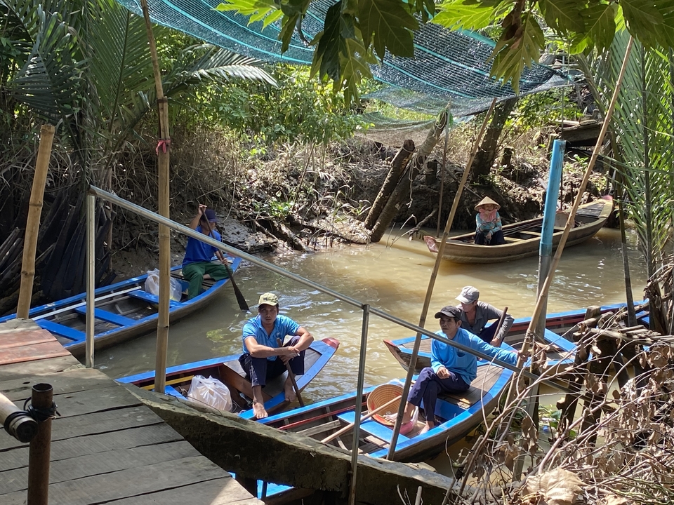 Des gens dans des bateaux le long d'une voie navigable étroite.
